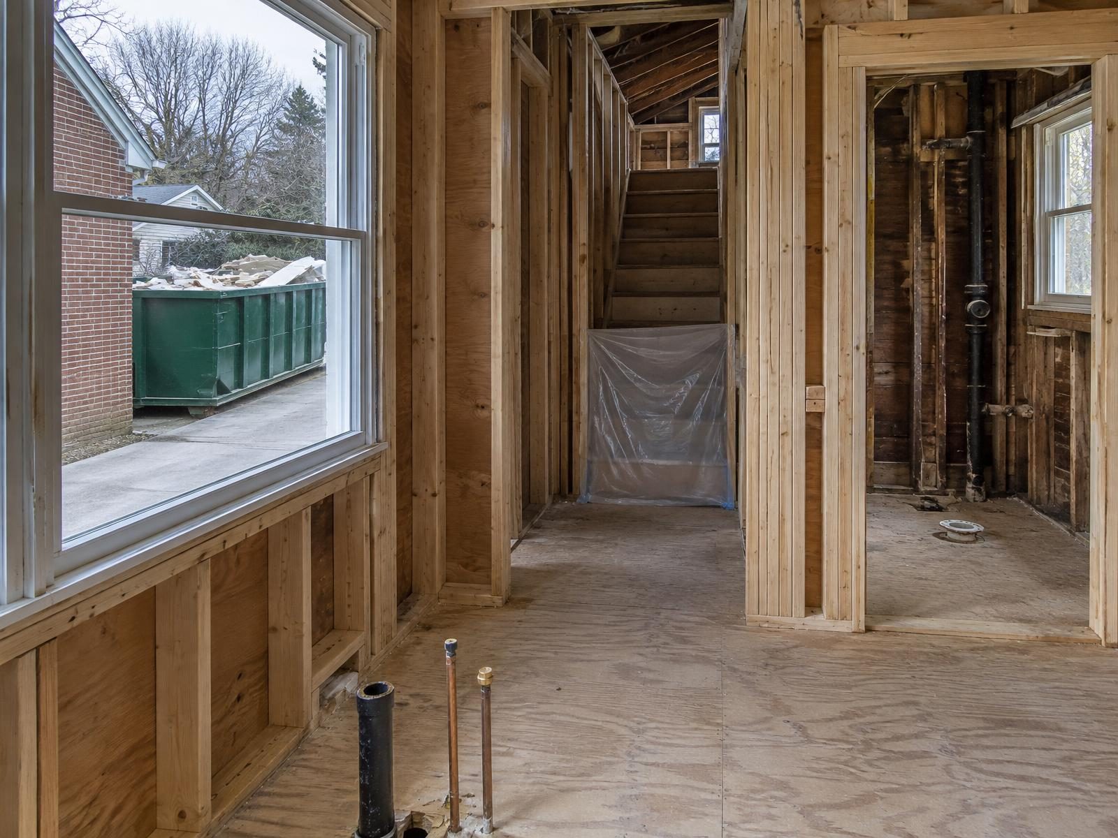 Illustration of a 1940s brick Cape Cod in Takoma Park in the middle of a whole-house renovation, with the kitchen and first-floor bath stripped to the studs, new wiring run through the upstairs dormer rooms and plastic sheeting hung across the stairway.