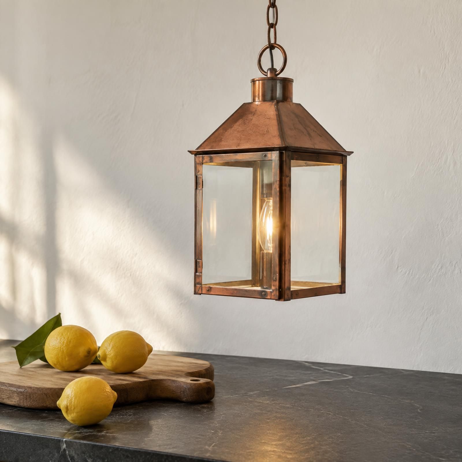 Illustration of a copper lantern pendant above a dark soapstone counter against a white wall.