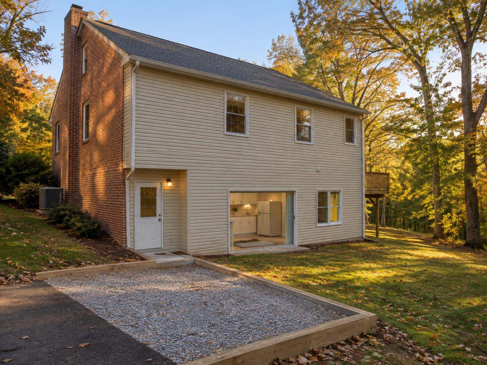 Illustration of a 1980s Fairfax County colonial on a sloping lot whose walkout basement has become an accessory apartment, with its own door at the side of the house, a kitchenette inside and an extra parking space beside the driveway.
